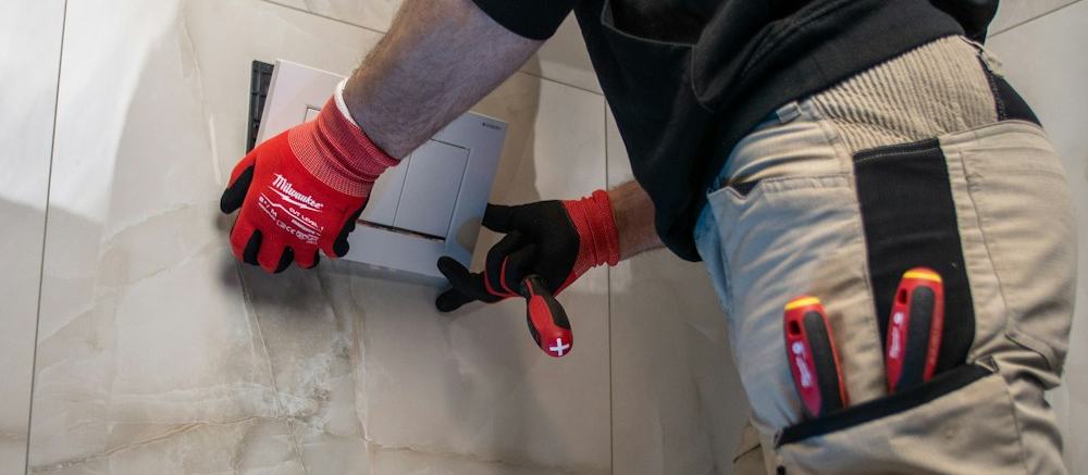 A plumber working on a wall-hung toilet